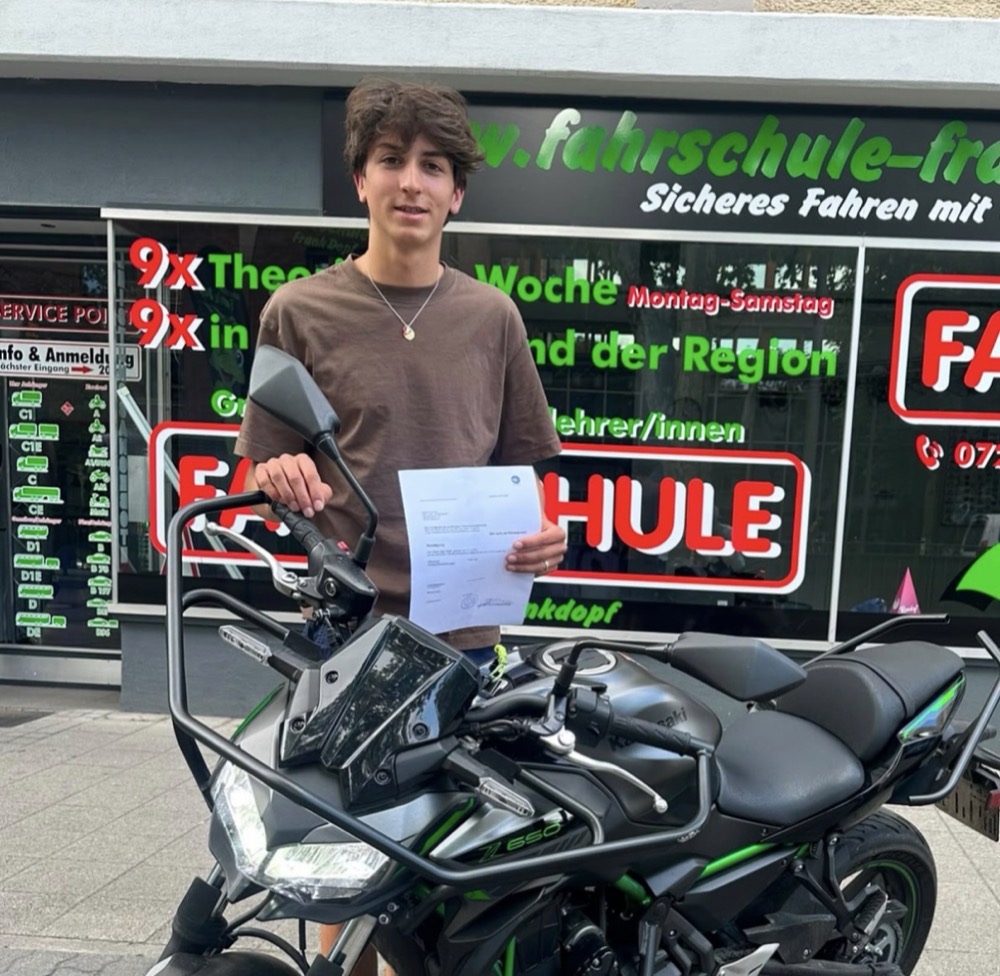 Motorrad-Fahrschüler mit Prüfungsbescheinigung vor der Filiale